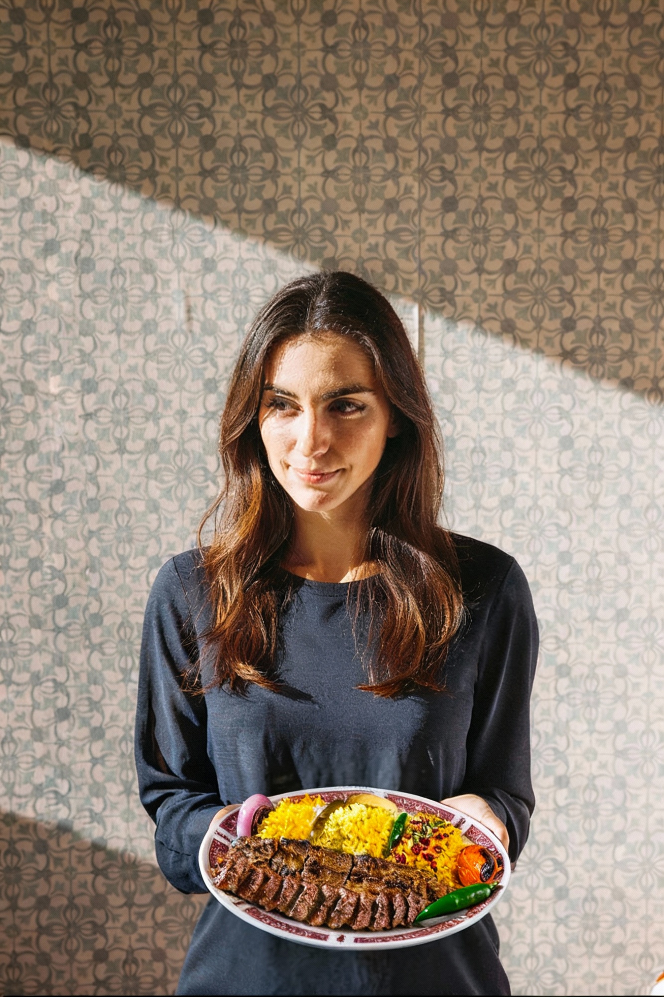 Woman holding a plate of Persian grilled kebab with rice at Crystal Restaurant in Croydon.